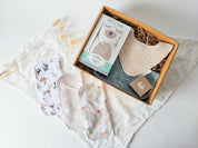 Boîte cadeau Petit trésor pour nouveau-né avec ourson chaud-froid Béké bobo, bavoir absorbant, débarbouillette douce et savon naturel, présentée sur couverture en mousseline, idée cadeau naissance pratique et unisexe.