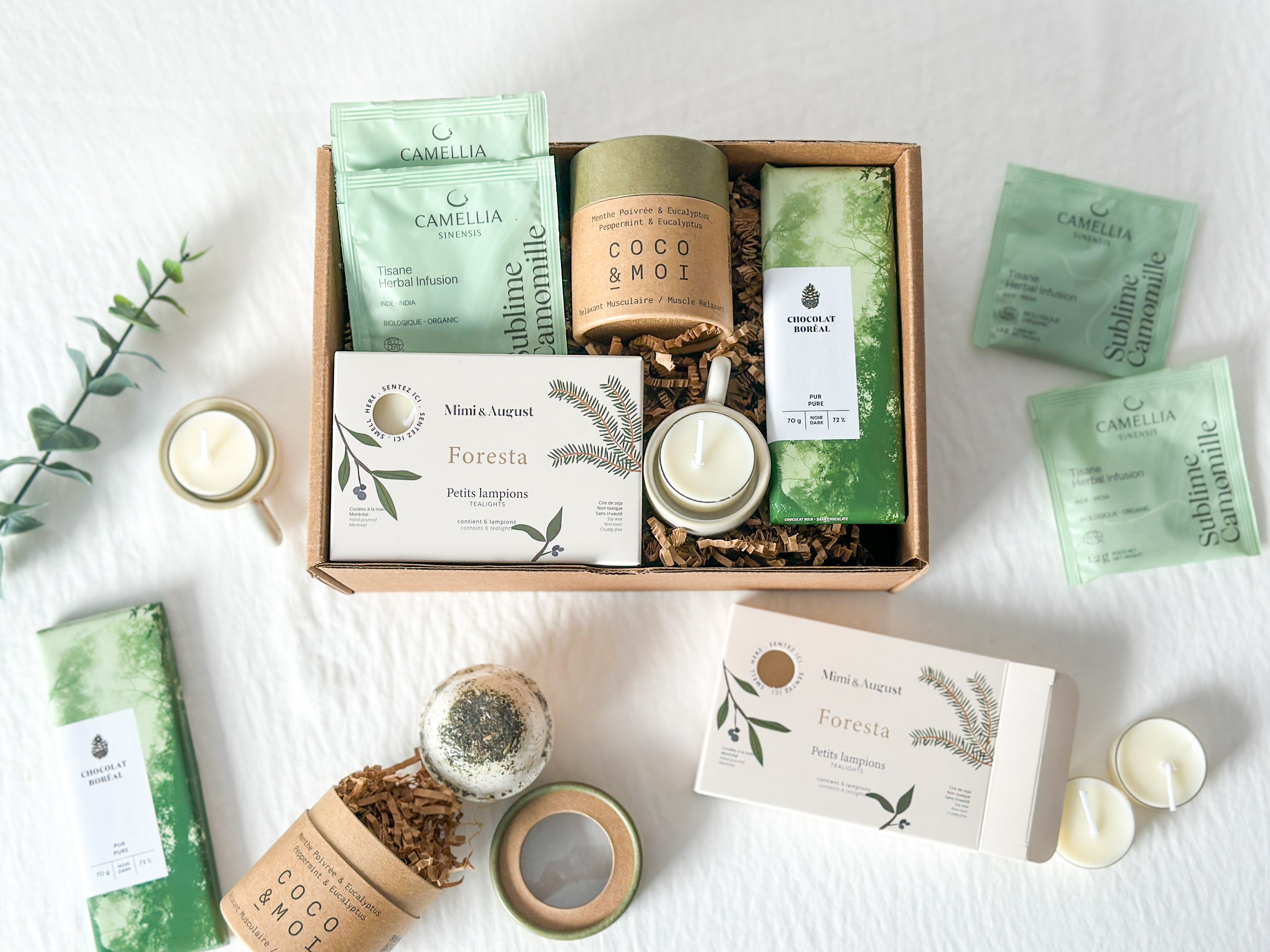 Boîte cadeau « Dans nos pensées » pensée pour offrir réconfort et douceur en période de deuil ou de moment difficile, avec lampions Mimi & August, bougeoir en bois Kotmo, chocolat noir 72 % Chocolat Boréal, tisane camomille Camellia Sinensis et bombe de bain Coco & Moi.