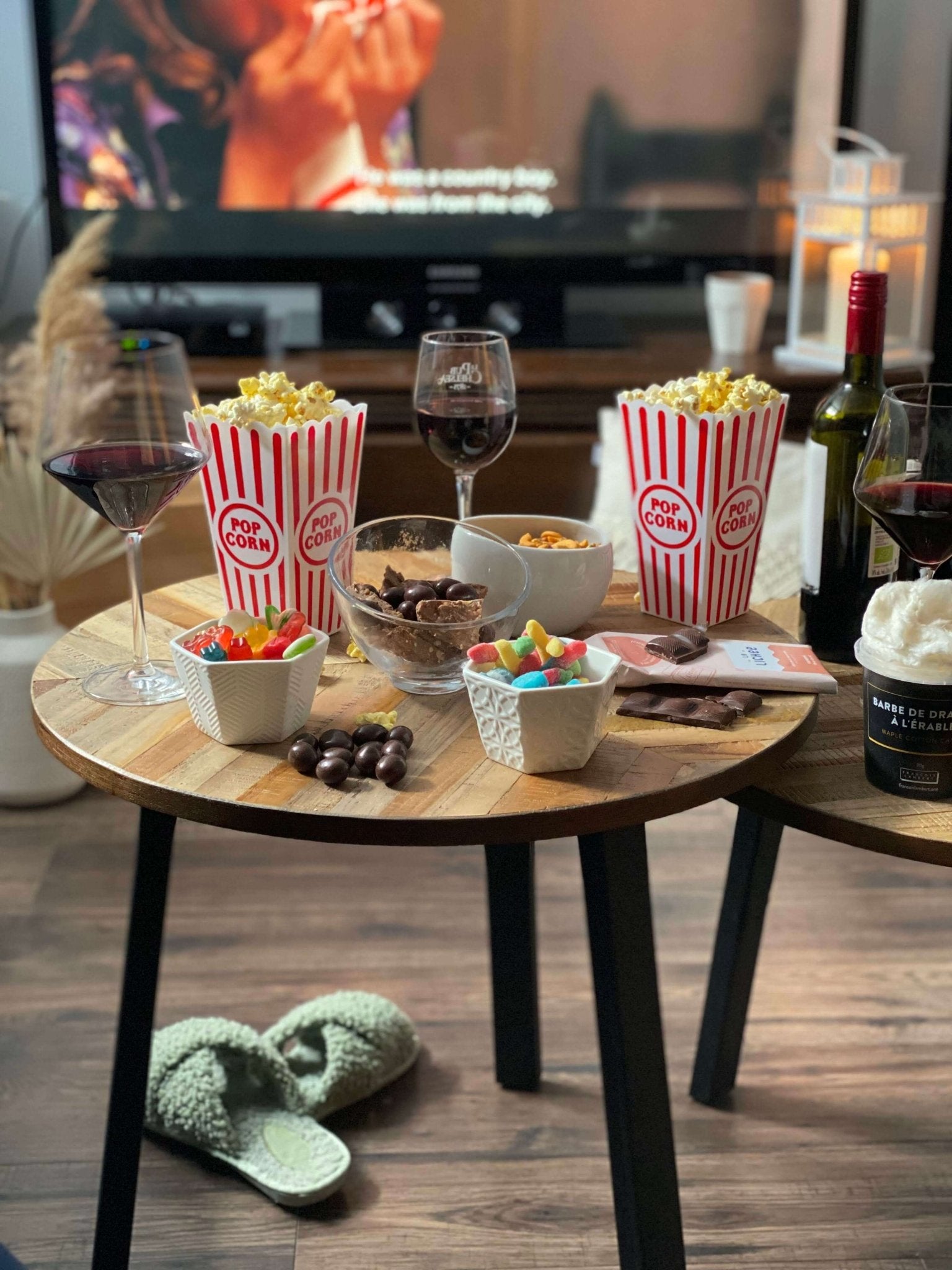 Soirée cinéma maison avec popcorn, bonbons, chocolat et verres de vin devant la télévision